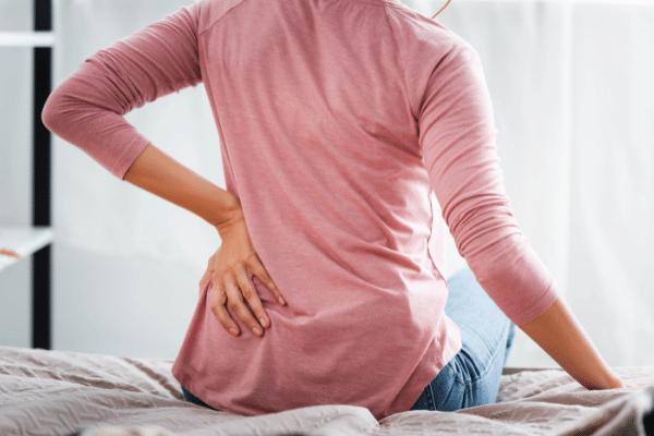 Mujer con dolor de espalda crónico sentada en una cama